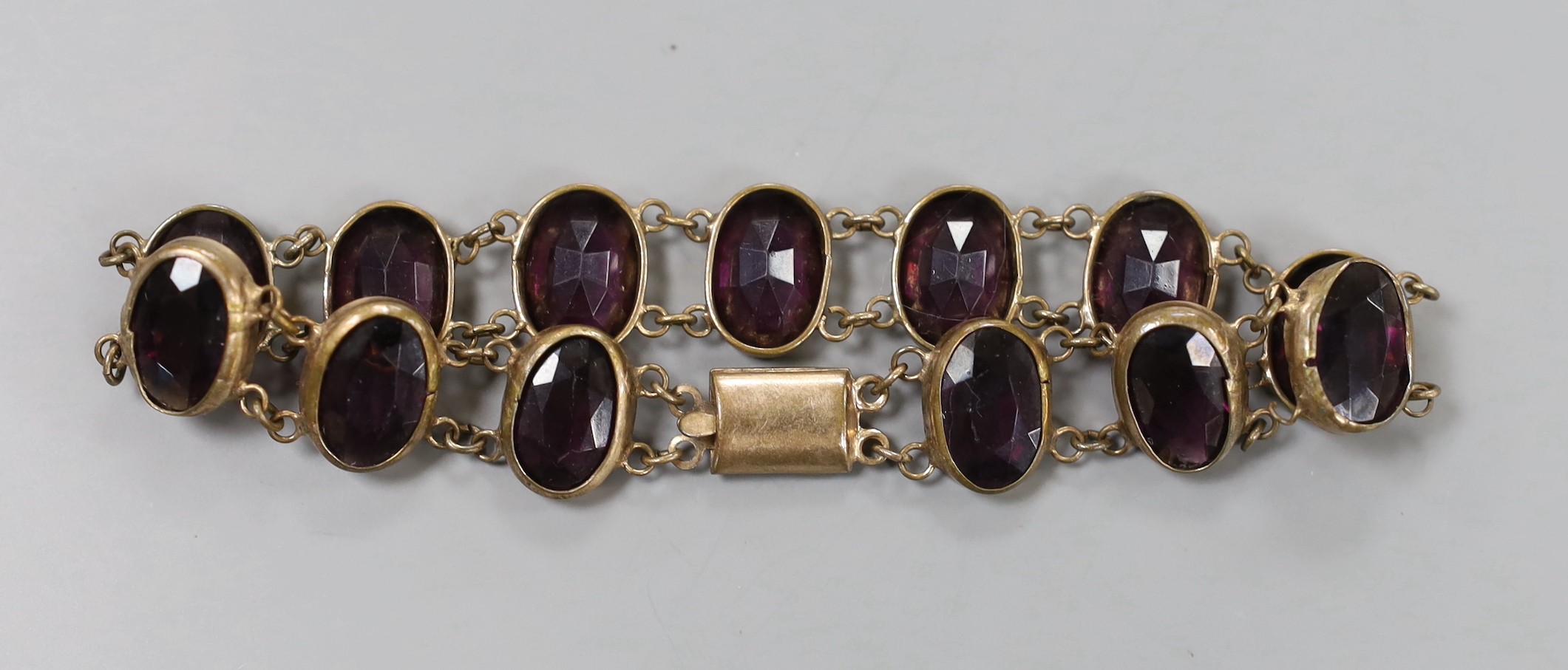 An Edwardian gilt metal and amethyst paste set bracelet, 21cm.